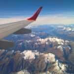 Uitzicht over de besneeuwde Alpen langs de vleugel van een Helvetic Airways-toestel