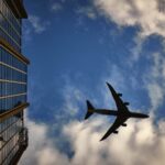 Boeing 747 vliegt langs een glazen kantoorgebouw met weerspiegeling in de gevel