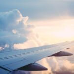 Vliegtuigvleugel met winglet boven de wolken bij laagstaande zon