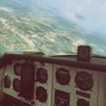 Cockpit van een eenmotorig sportvliegtuig met uitzicht op de stad